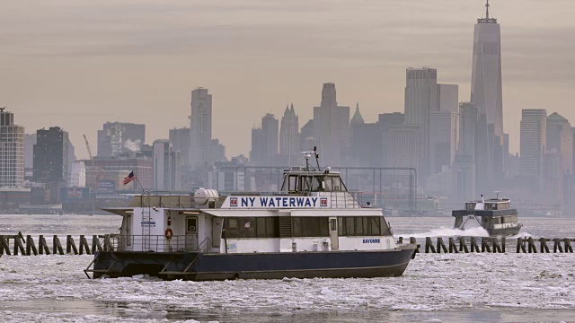 在曼哈顿下城的地平线上，纽约水道的渡船穿过结冰的哈德逊河。视频素材