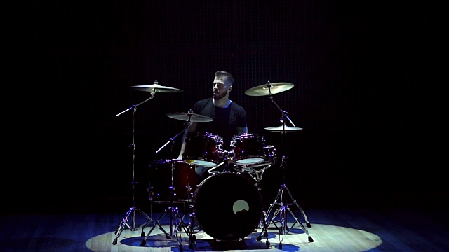 鼓手在黑色背景上打鼓。视频素材