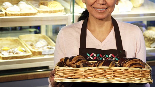 一名快乐的女面包师抱着一篮子羊角面包的照片视频素材