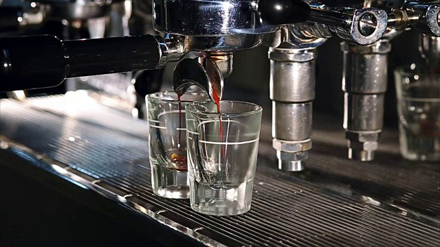 专业意式浓缩咖啡机在酒吧冲泡咖啡。咖啡倒入小酒杯。调色视频，实时。意大利传统的早餐短饮。视频下载