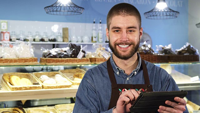 英俊的职业男面包师在他的店里使用数码平板电脑视频素材