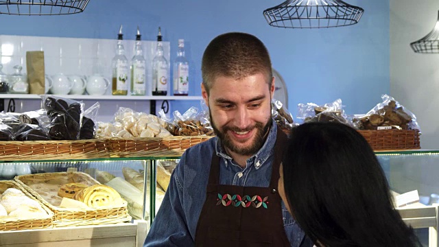 专业的男面包师在他的店里帮助他的成熟的女性顾客视频素材