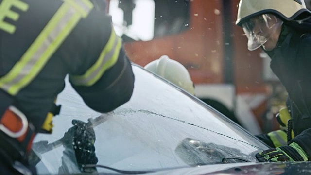 消防队员切开一辆汽车的挡风玻璃以拯救受伤的乘客视频素材