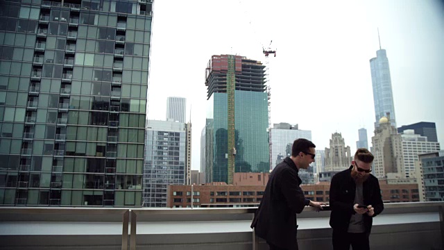 两个朋友在芝加哥的屋顶上用智能手机自拍，大笑着俯瞰城市的天际线。视频素材
