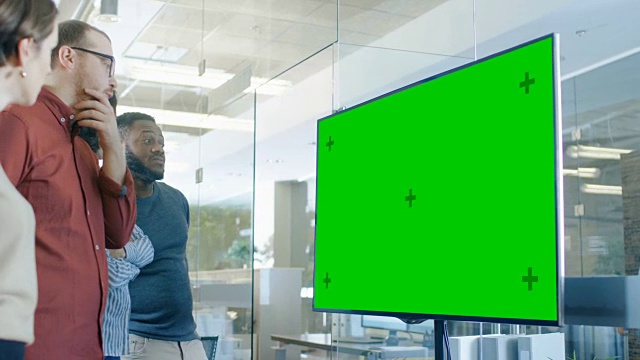 一群年轻人在会议室讨论模拟彩色键绿屏电视。视频素材
