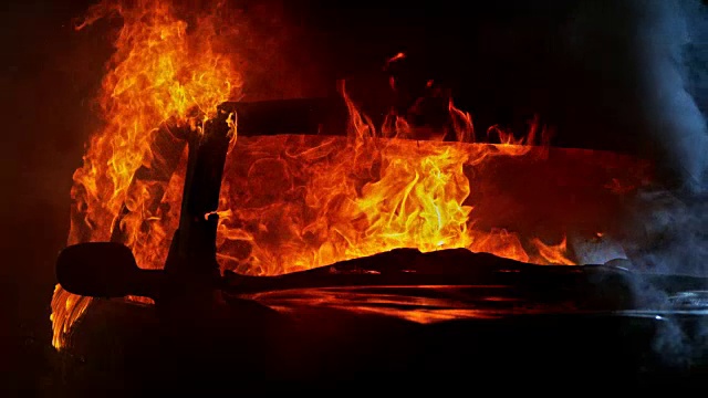 SLO MO一辆汽车在晚上着火，冒出滚滚的火焰视频素材
