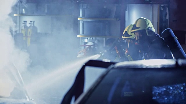 两名消防队员在夜间将汽车大火扑灭视频素材