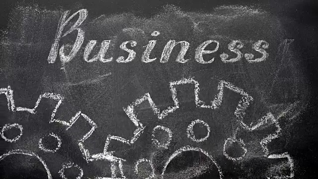 黑板上用粉笔书写商业和金融的概念，文字“商业”，以及动画旋转的两个粉笔剪影绘图齿轮。视频素材