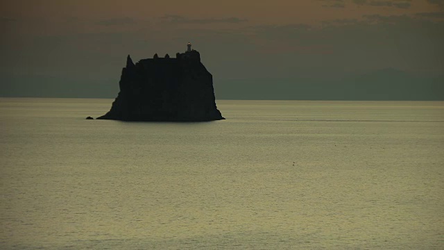 意大利第勒尼安海，一座石岛上的灯塔在晨曦朦胧中闪烁着光芒。视频素材