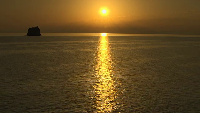 太阳在日出时照射到第勒尼安海的一个岩石岛附近。视频素材