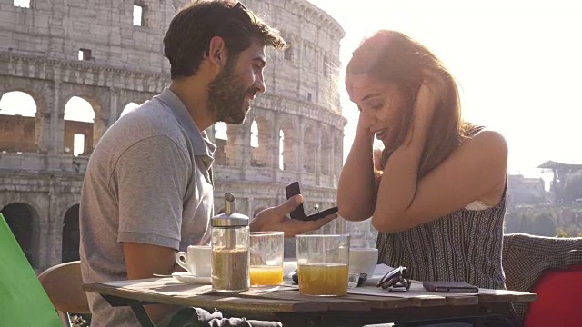这对幸福的情侣带着戒指坐在罗马斗牛场前的餐厅里，夕阳西下时情绪激动视频下载