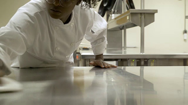 在餐饮学院清洁工作台面的年轻女子。视频素材
