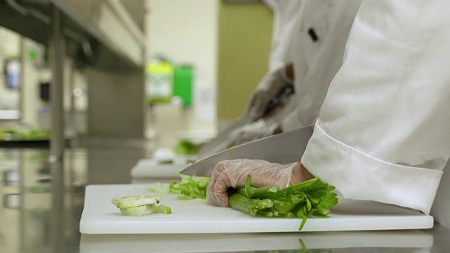 在商业厨房里切新鲜芹菜的女人，特写。视频素材