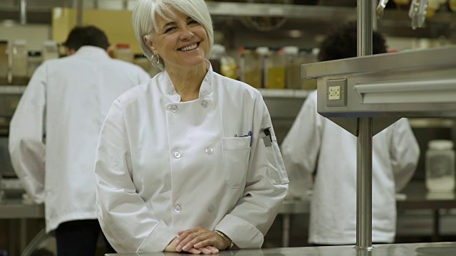 女餐饮学生穿着厨师制服对着镜头微笑。视频素材