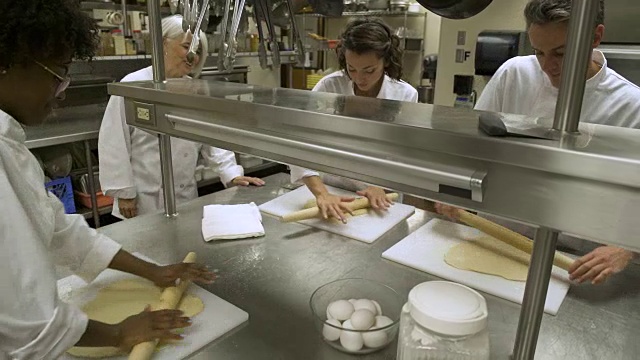 餐饮学生学习如何在商业厨房卷糕点。视频素材