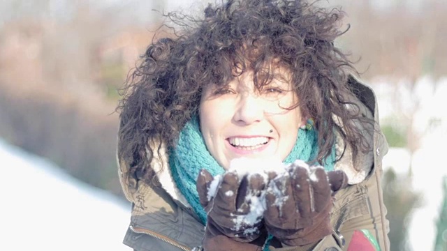 美丽的白人女人在冬天吹雪，雪视频素材