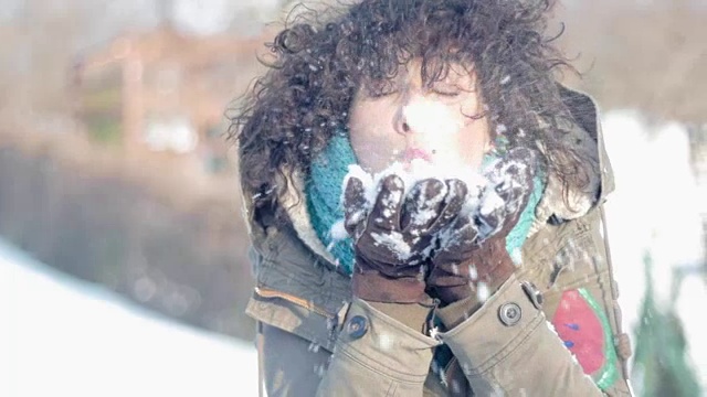 美丽的白人女人在冬天吹雪，雪视频素材