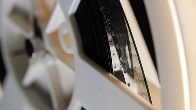老式8毫米电影放映机在晚上播放。影片的特写镜头。在录象机、录音机或播放机上带磁带的旋转盘视频素材