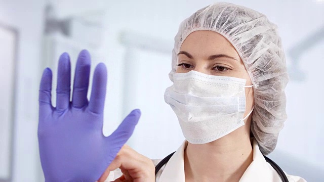 专业女医生在病房里戴医用手套。在职女医生视频素材
