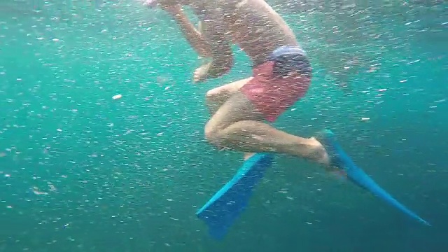 一对男女和蝠鲼在蓝绿色的大海里浮潜。——慢动作视频素材