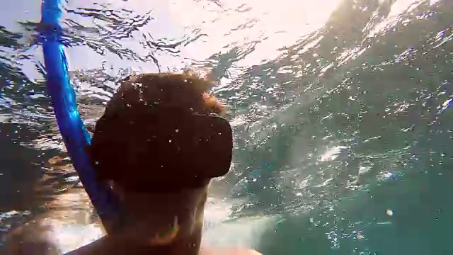 一名男子在水下潜水时自拍，并做了一个友好的“沙卡”手势。——慢动作视频素材