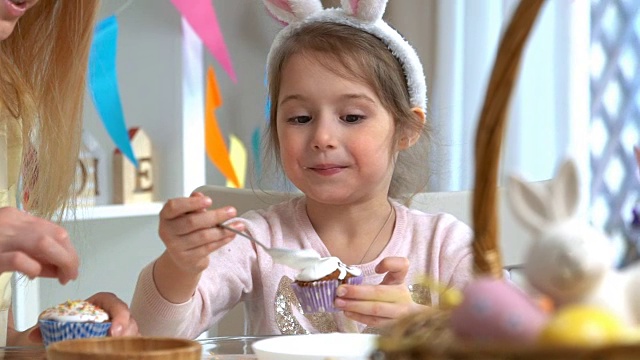 年轻的母亲和她的女儿戴着兔子耳朵做复活节纸杯蛋糕视频素材