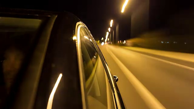 在一辆驾驶的德国黑色汽车上，时间流逝拍摄了蓝色的小时和夜晚，相机看着驾驶方向，前景中有反射的窗户，背景是运动模糊，男性司机通过挡风玻璃部分看到视频素材