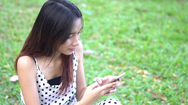 亚洲年轻女子在花园里玩智能手机视频素材