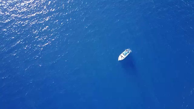 在毛伊岛海岸，一艘孤独的船漂浮在无人机的有利位置之下视频素材