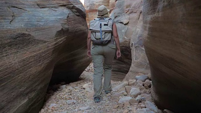 女人徒步旅行干河峡谷与平滑和波浪的岩石的峡谷4K视频素材