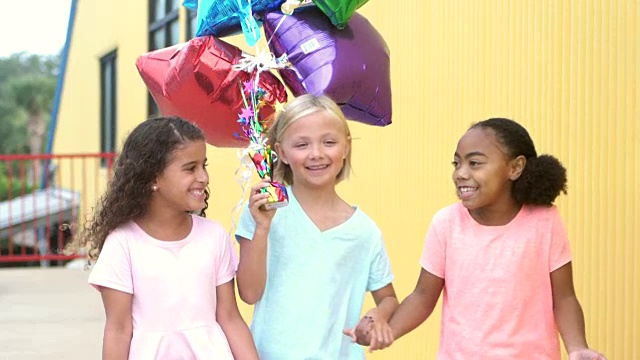 三个女孩手牵着手拿着气球走视频素材
