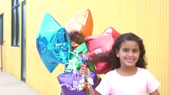混血女孩拿着一堆气球跑过视频素材