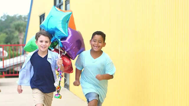 两个男孩拿着一堆氦气球跑视频素材