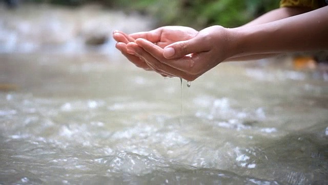 慢镜头:一个女人在瀑布边洗手视频下载