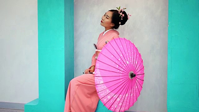 粉红色的艺妓坐在墙边，把伞烂掉了。视频下载