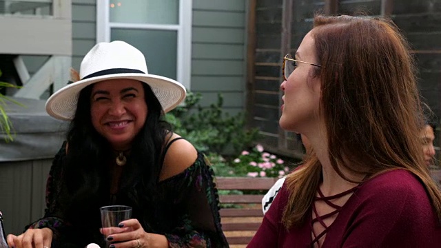 夏天的晚上，一群大笑着分享食物和饮料的女人在外面视频素材