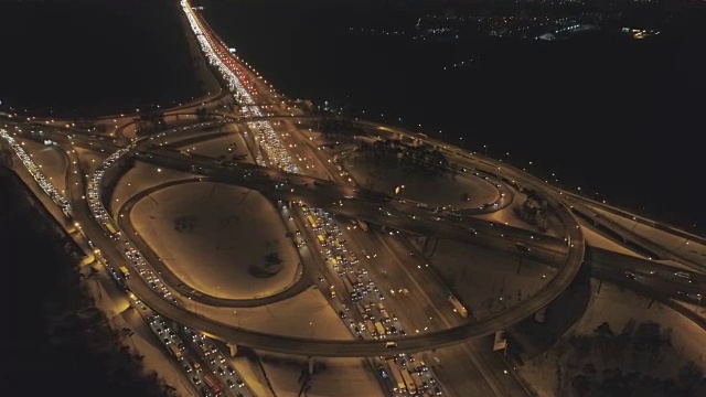 照明复杂的公路路口和汽车在冬夜塞车。无人机正在轨道上运行，摄像头正在向下倾斜。鸟瞰图。远景。视频素材