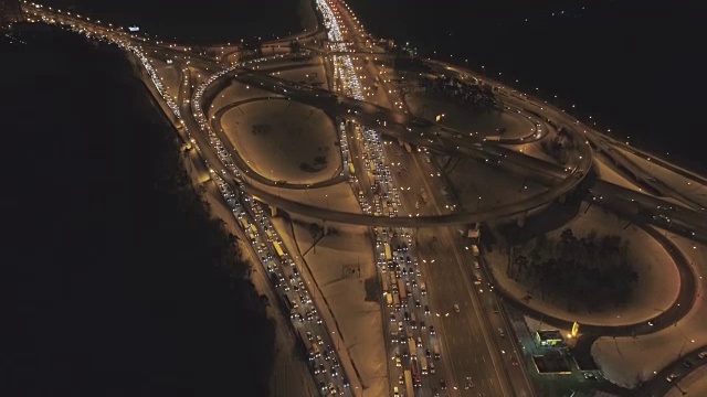 照明复杂的公路路口和汽车在冬夜塞车。无人机正在向上飞行。鸟瞰图。建立揭示。视频素材