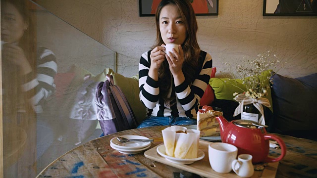 年轻女子在咖啡店吃蛋糕喝茶视频素材