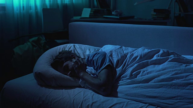 可爱的男生晚上睡在舒适的床上，健康的睡眠和放松视频素材