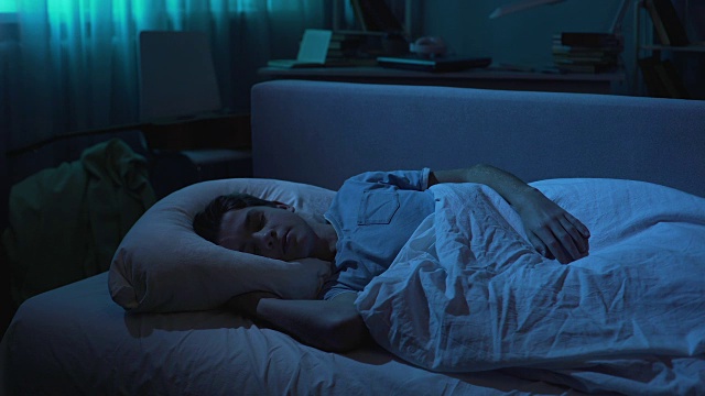 疲惫的年轻人在辛苦工作一天后，穿着白色t恤睡在他的床上视频素材