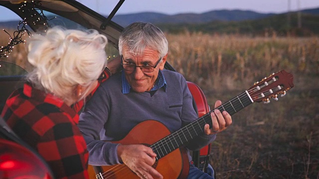 浪漫的老男人为漂亮的老女人弹吉他视频素材