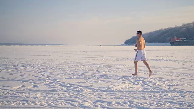 一个健康的人赤脚在雪地上跑步。视频素材