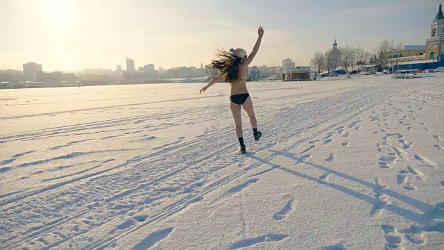 一个穿着比基尼的长发女人在雪地上跳跃。视频素材