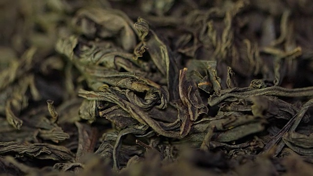 茶药材质地。绿茶。有机干绿茶叶。一堆干绿茶的背景。宏视频下载
