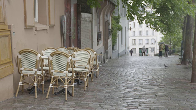 这张照片拍摄于法国巴黎一条铺满鹅卵石的街道上的柳条桌椅视频下载