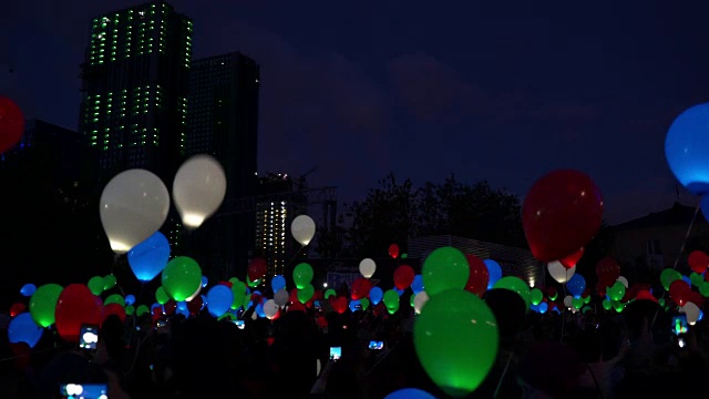 爱的盛宴的概念。在夜晚城市的天空中飞行的彩色氦气发光的气球视频下载