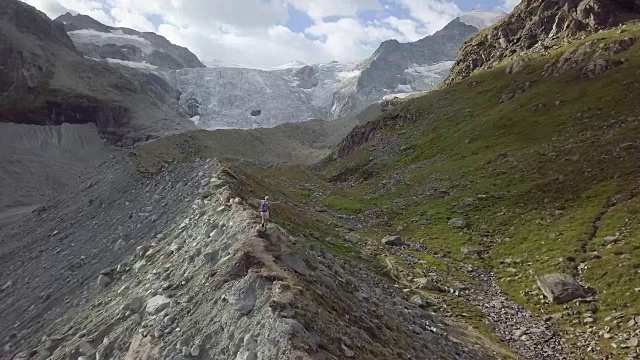 鸟瞰山脊上的女性徒步者走向冰川，无人机天桥视频素材