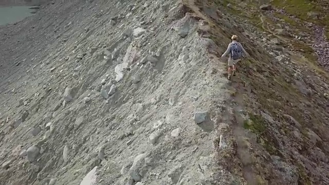 一名年轻女子在瑞士的山脊上徒步旅行的无人机镜头视频下载