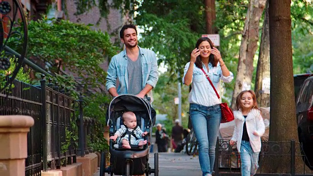 一个快乐的年轻家庭走在布鲁克林的大街上视频素材